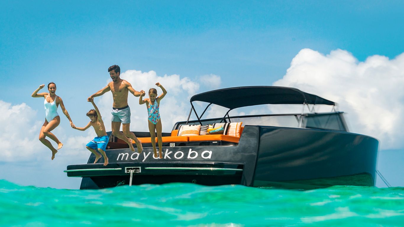 Mayakoba_Family holiding hands and jumping off yacht int turquiose ocean